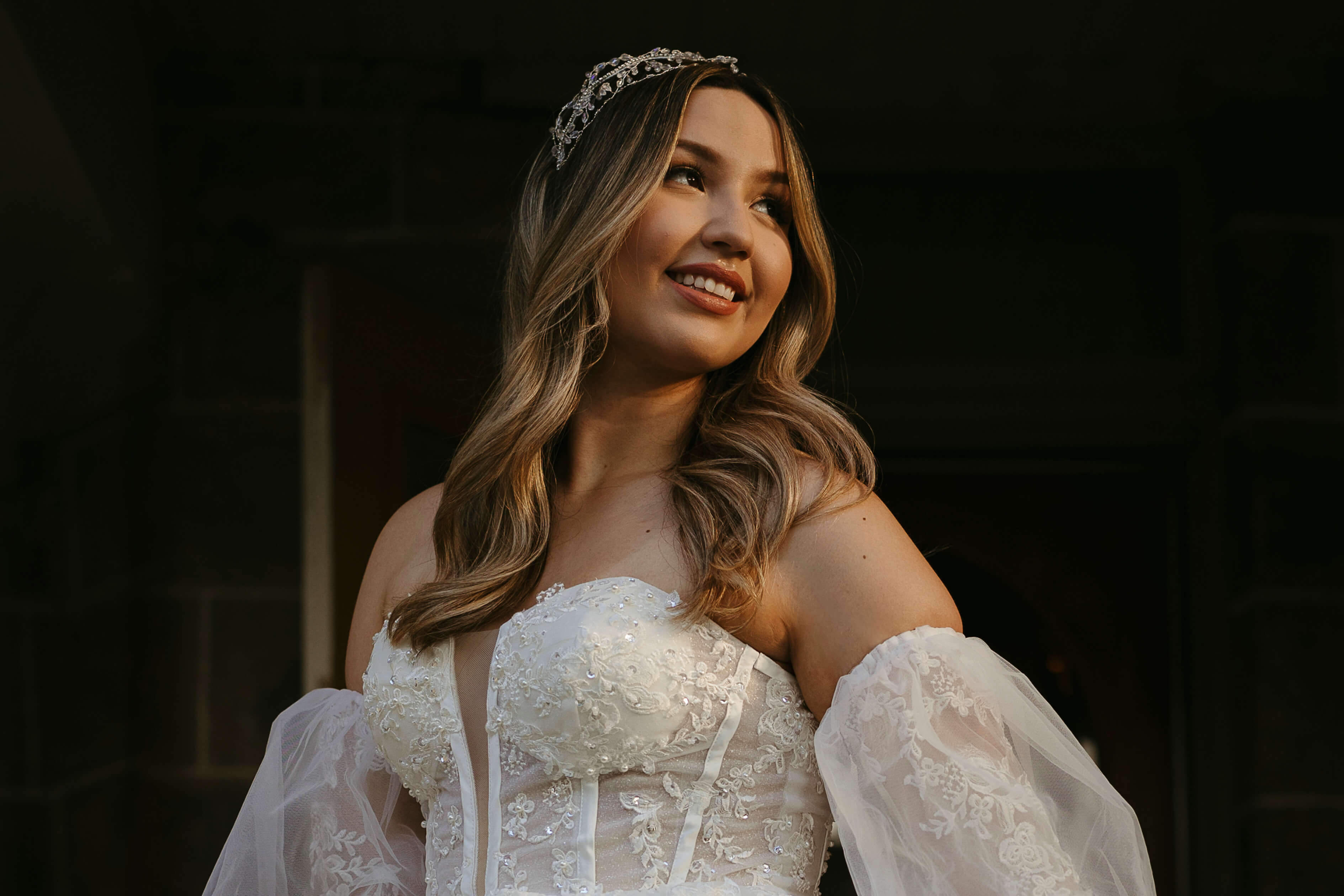 Bride standing at Bella's Castle entrance, holding her white dress with her hair down.